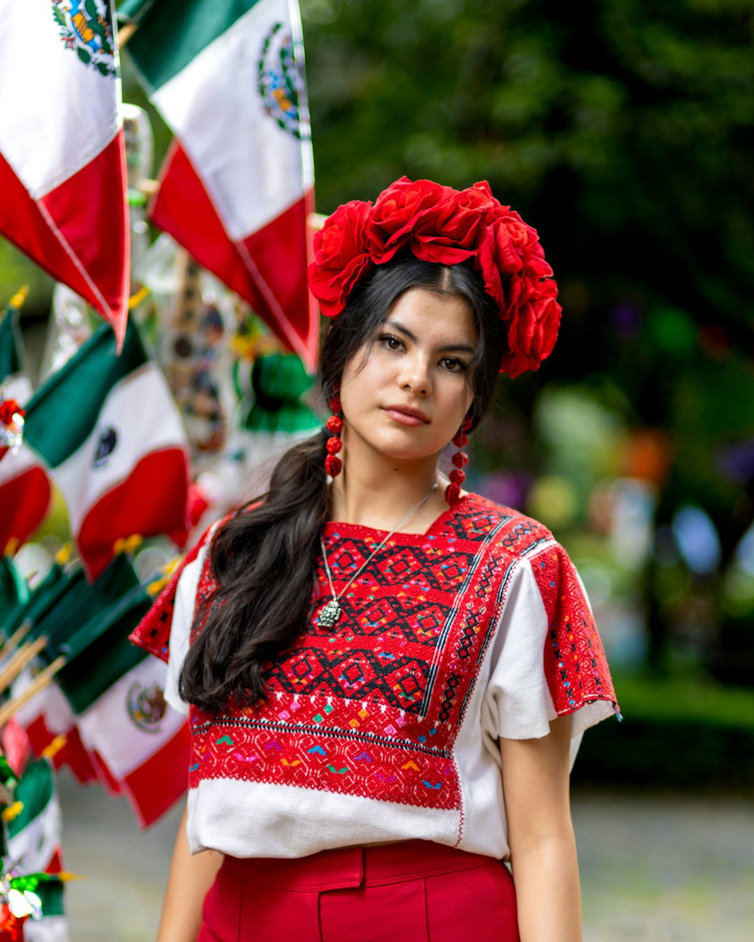 a woman in a mexican outfit standing in front of flags
