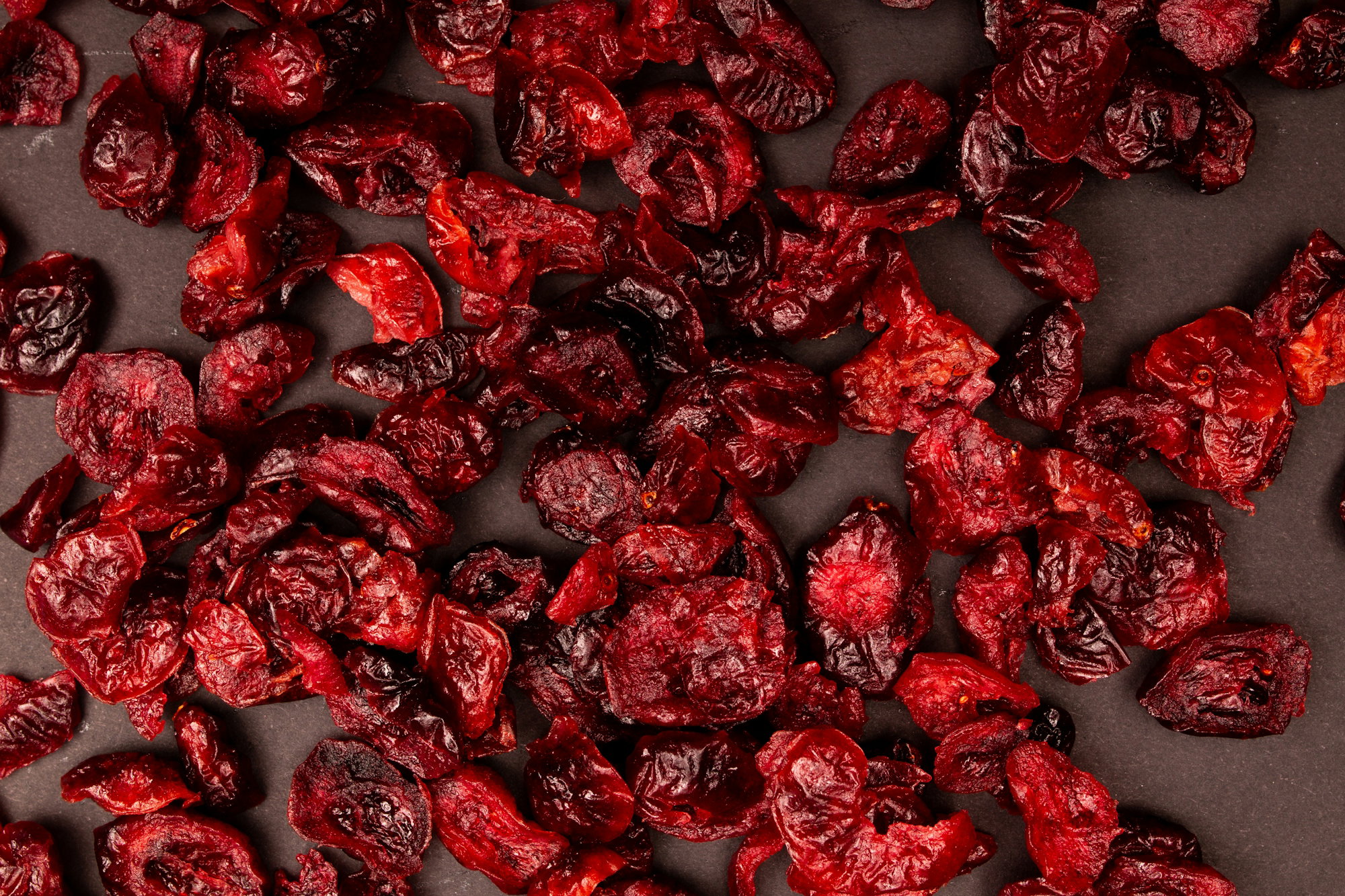 Dried cranberries scattered on a dark surface